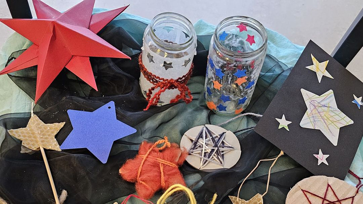 Verschiedene Sterne aus Papier und Wolle sowie verzierte Gläser mit Sternmotiven, die beim LamiKita-Sternstunden-Event verkauft wurden.