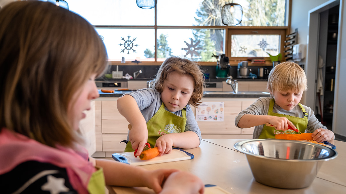 LamiKita Kinder schählen Karotten in der Küche